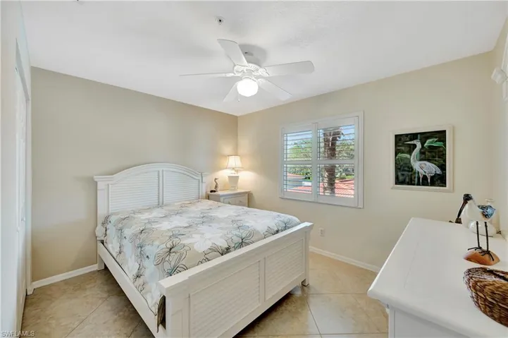 Tiled bedroom featuring ceiling fan