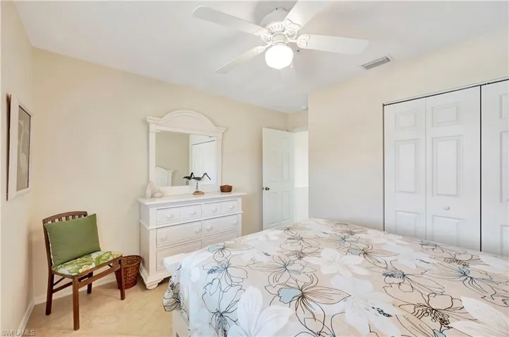 Tiled bedroom with ceiling fan and a closet
