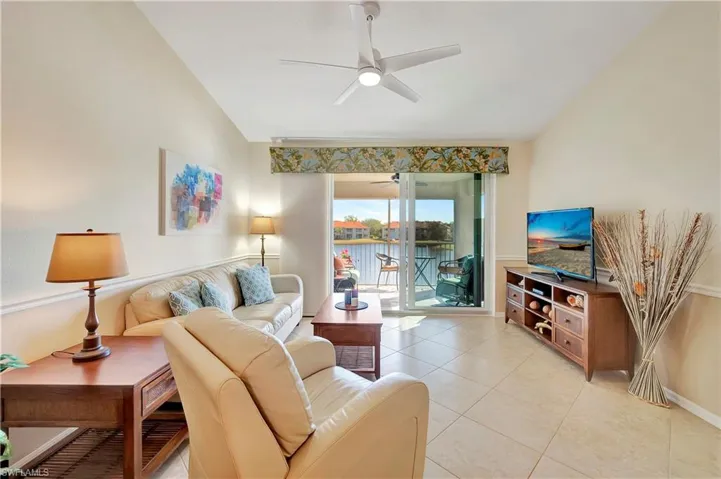 Living room featuring vaulted ceiling, ceiling fan, and light tile patterned flooring