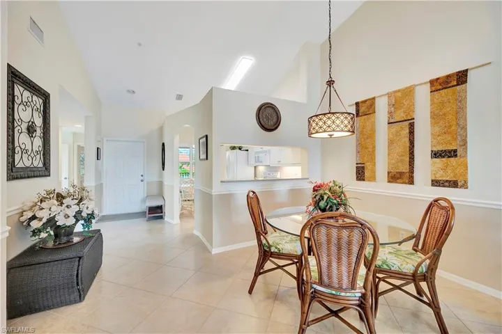 Tiled dining space featuring high vaulted ceiling