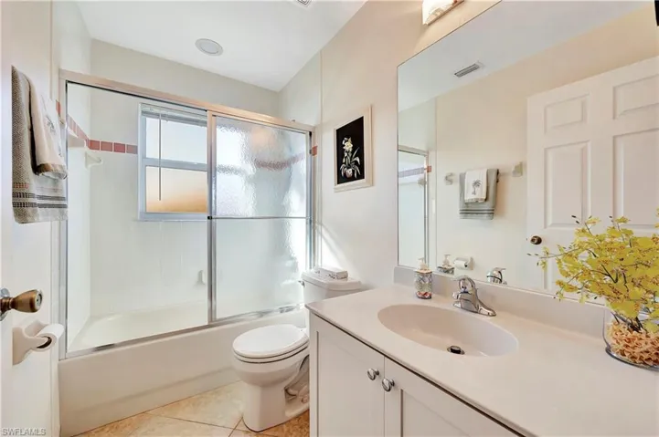 Full bathroom featuring tile patterned floors, toilet, vanity, and combined bath / shower with glass door