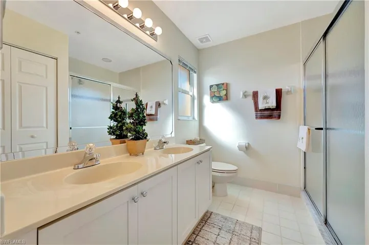Bathroom with toilet, vanity, tile patterned floors, and a shower with door