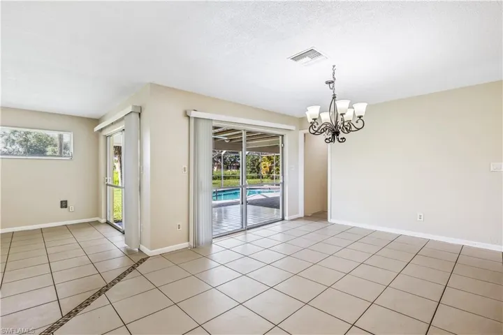 Unfurnished room featuring an inviting chandelier, light tile patterned floors, and plenty of natural light