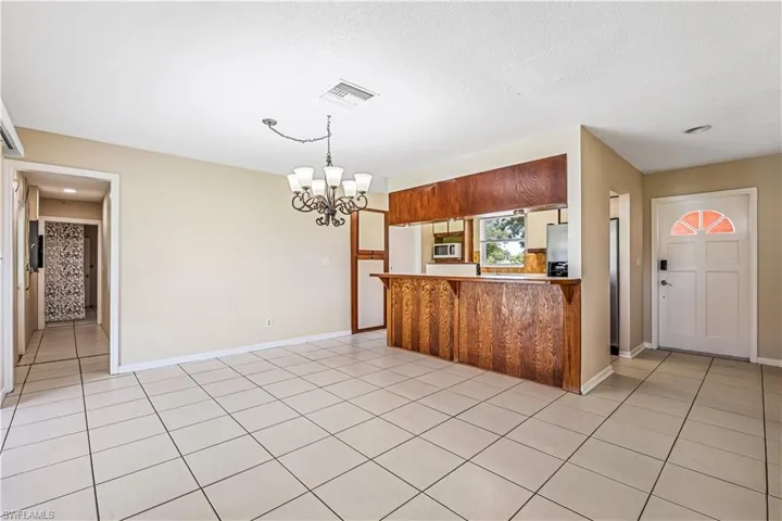 Kitchen with stainless steel microwave, light tile patterned flooring, a breakfast bar area, and a chandelier