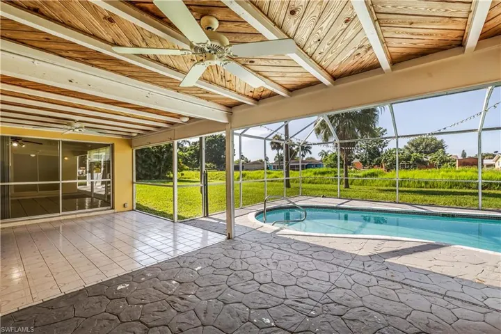 View of pool featuring ceiling fan, a patio, a lanai, and a yard