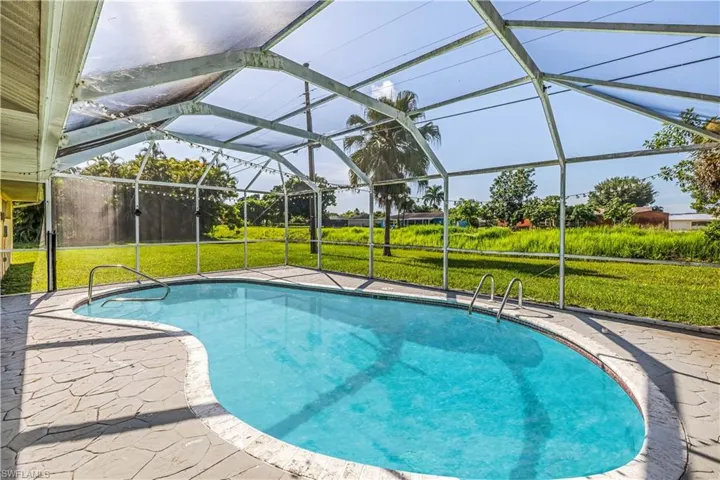View of swimming pool featuring a lanai, a patio area, and a yard