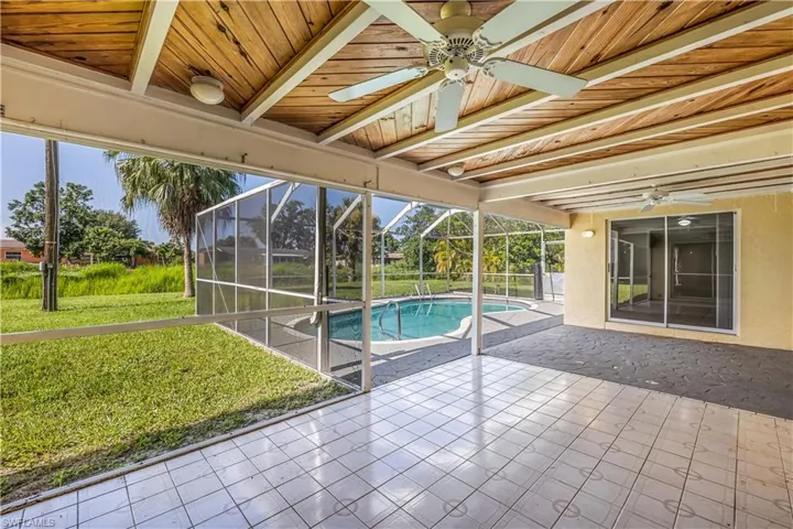 Unfurnished sunroom with ceiling fan, beamed ceiling, and wooden ceiling