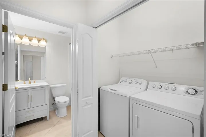 Bathroom with vanity, washer and dryer, and light tile patterned floors