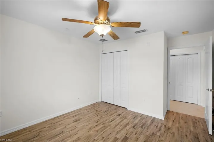 Unfurnished bedroom with light wood-type flooring, ceiling fan, and a closet