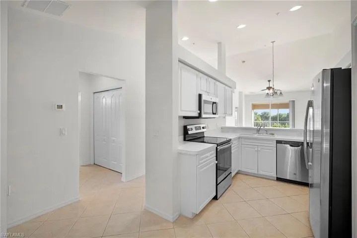 Kitchen with stainless steel appliances, light countertops, white cabinetry, and light tile patterned flooring