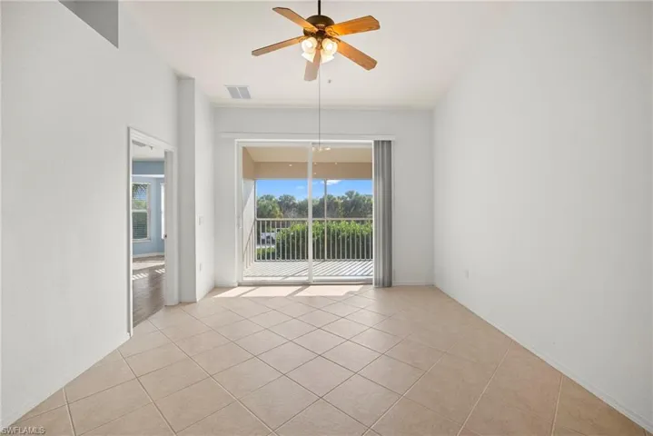 Empty room with a ceiling fan and light tile patterned flooring