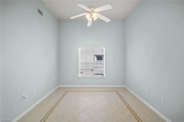 Spare room with a ceiling fan, inlaid floor details, and light tile patterned flooring