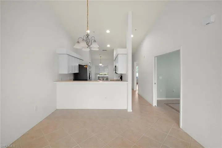 Kitchen with white cabinets, a peninsula, light tile patterned floors, suspended lighting, and light countertops