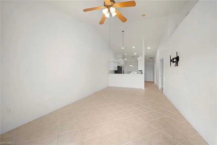 Unfurnished living room with light tile patterned floors, a ceiling fan, and lofted ceiling