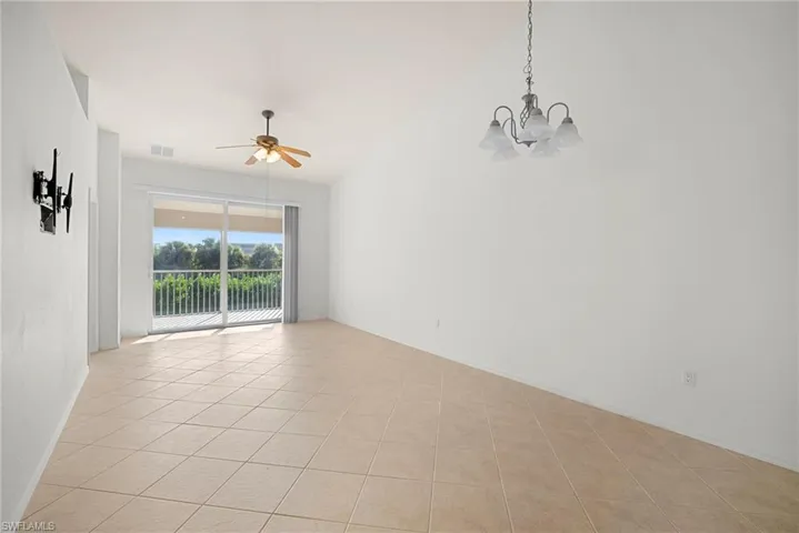 Spare room featuring suspended lighting, ceiling fan, light tile patterned flooring, and lofted ceiling
