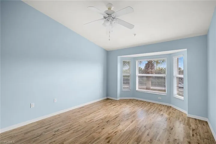 Unfurnished room with ceiling fan, light wood-style flooring, and vaulted ceiling