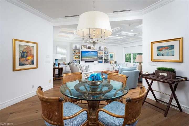 Dining area with coffered ceiling, wood-type flooring, a chandelier, beamed ceiling, and ornamental molding