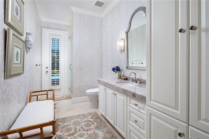 Full bathroom with vanity, crown molding, a shower stall, and wallpapered walls