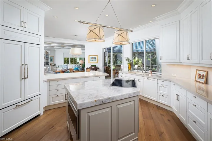Kitchen with a kitchen island, pendant lighting, light stone countertops, recessed lighting, and white cabinetry