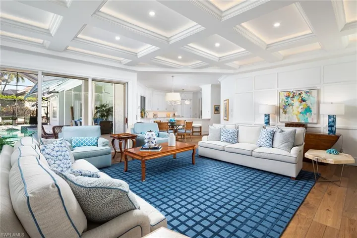 Living room featuring coffered ceiling, hardwood / wood-style flooring, beamed ceiling, and ornamental molding