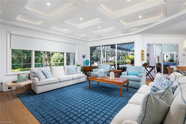 Sunroom featuring hardwood / wood-style floors, coffered ceiling, healthy amount of natural light, beam ceiling, and crown molding