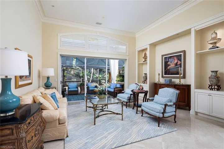 Living room with built in features, a towering ceiling, and crown molding