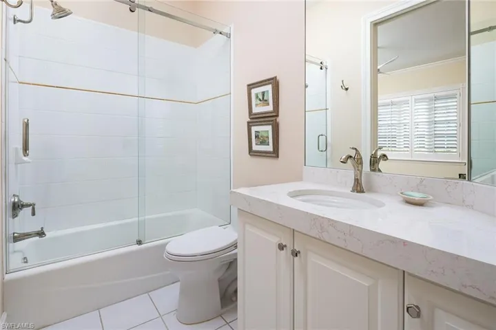 Full bath with vanity, shower / bath combination with glass door, light tile patterned floors, and ornamental molding