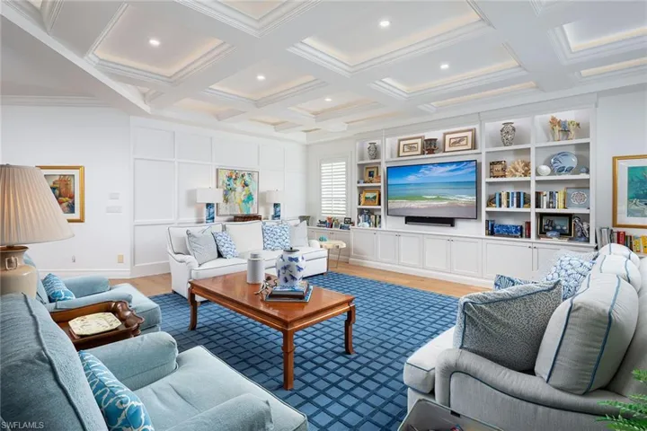 Living room with light wood-style flooring, coffered ceiling, beamed ceiling, and ornamental molding