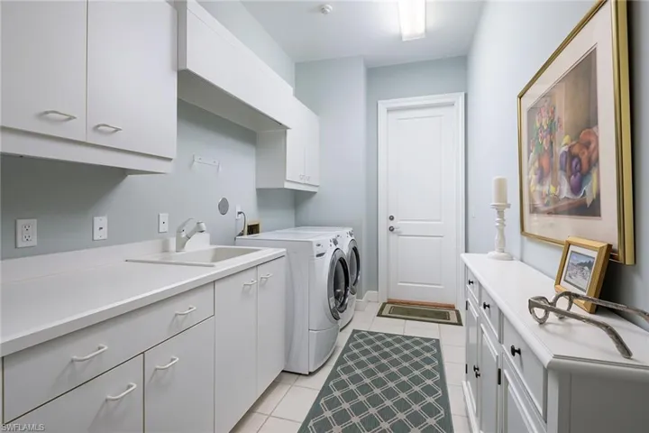 Laundry room featuring cabinet space, light tile patterned floors, and separate washer and dryer