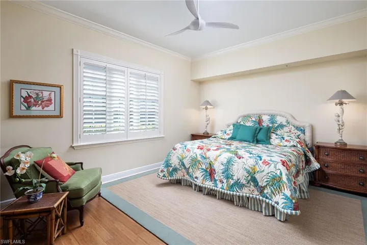 Bedroom with ornamental molding, a ceiling fan, and wood finished floors