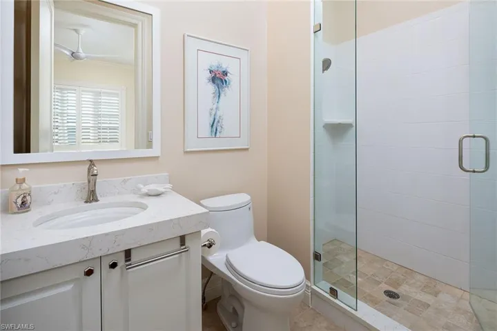 Bathroom with vanity, a stall shower, and ceiling fan