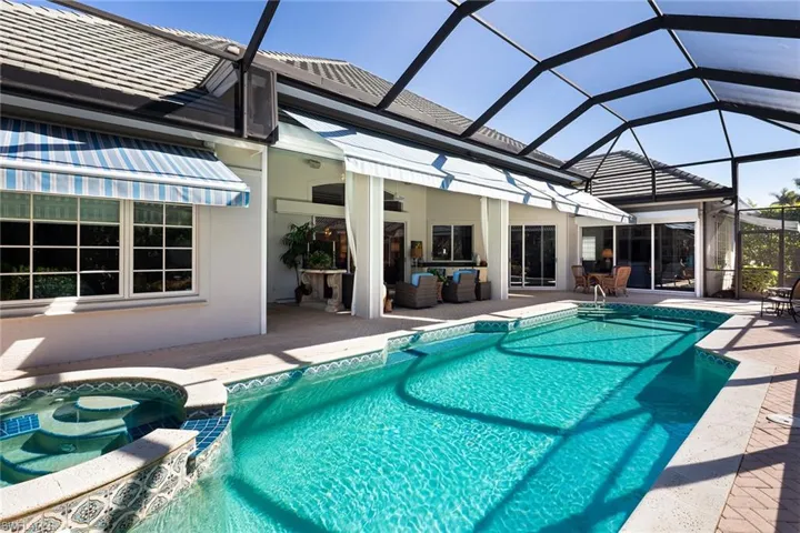 View of pool with a sunroom, glass enclosure, a patio, and a pool with connected hot tub