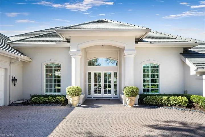 Property entrance featuring french doors, a tiled roof, stucco siding, and an attached garage