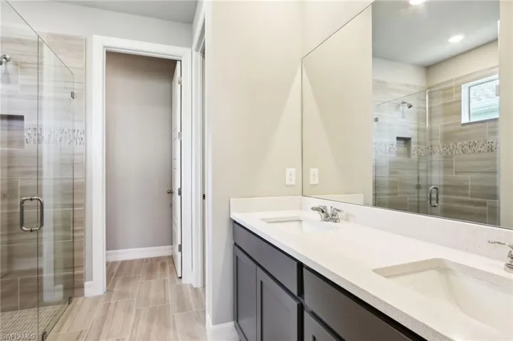 Bathroom featuring double vanity, a stall shower, recessed lighting, and baseboards