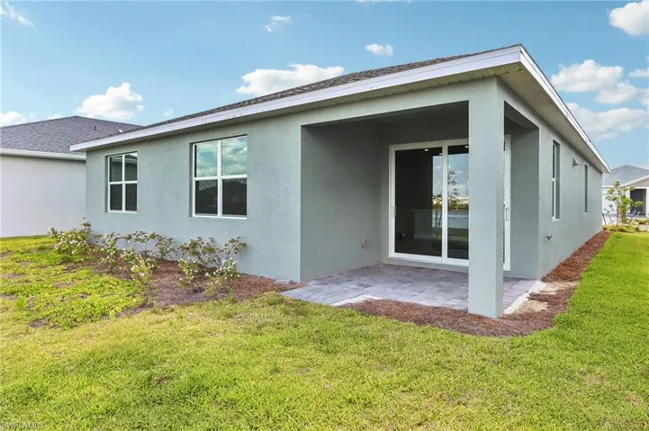 Back of house featuring stucco siding, a patio, and a lawn
