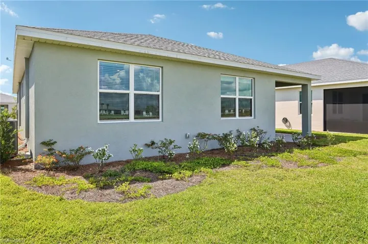 View of home's exterior featuring stucco siding, a lawn, and a shingled roof