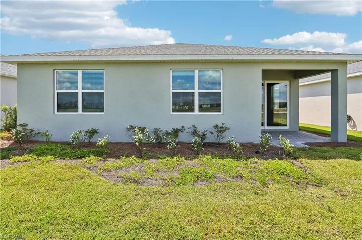 View of side of property featuring stucco siding, a yard, and a patio