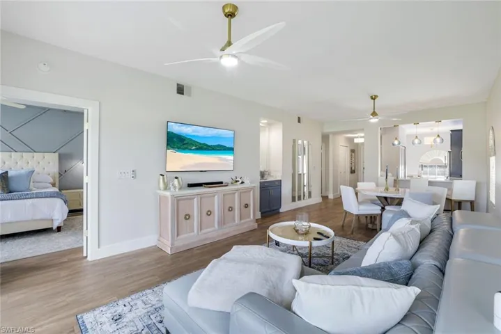 Living area featuring baseboards, visible vents, wood finished floors, and a ceiling fan