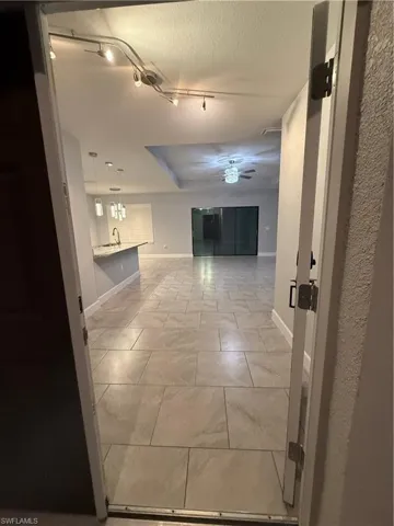 Hallway featuring a textured ceiling, track lighting, and sink