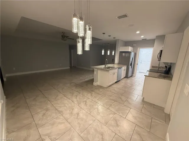 Kitchen featuring white cabinets, sink, hanging light fixtures, ceiling fan, and appliances with stainless steel finishes