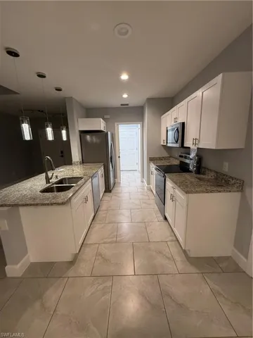 Kitchen with sink, pendant lighting, dishwashing machine, white cabinets, and range
