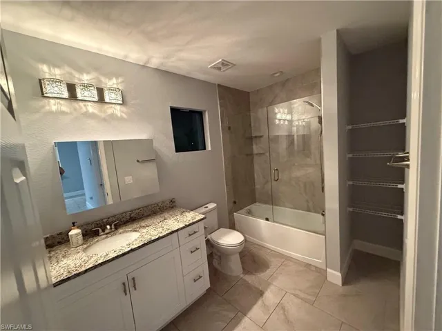 Full bathroom featuring vanity, toilet, and combined bath / shower with glass door
