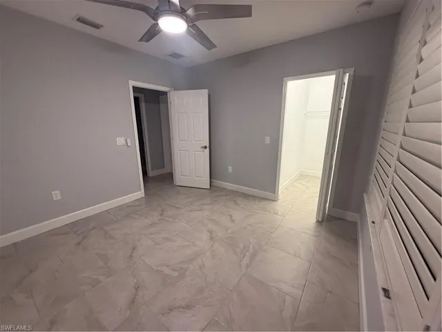 Unfurnished bedroom with marble finish floor, baseboards, visible vents, and a ceiling fan