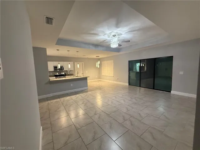 Unfurnished living room with ceiling fan and a raised ceiling
