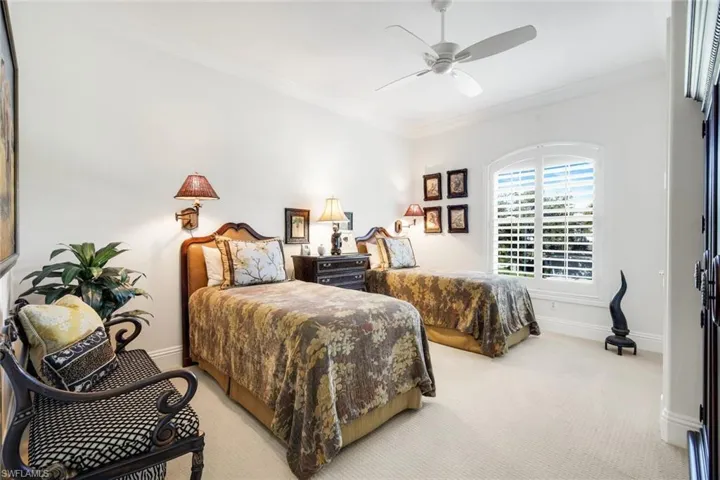 Carpeted bedroom with a ceiling fan and ornamental molding
