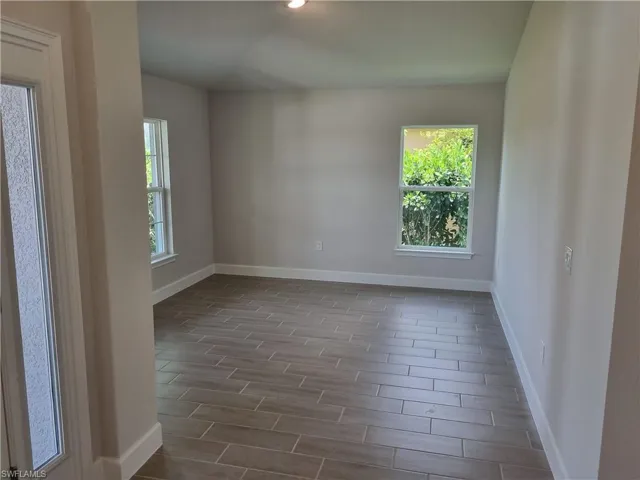 Unfurnished room with wood tiled floors, baseboards, and recessed lighting