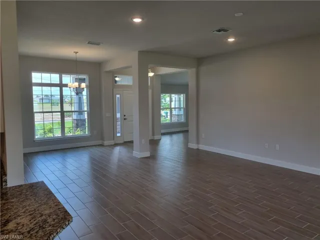 Unfurnished living room featuring baseboards, a chandelier, recessed lighting, and dark wood finished floors