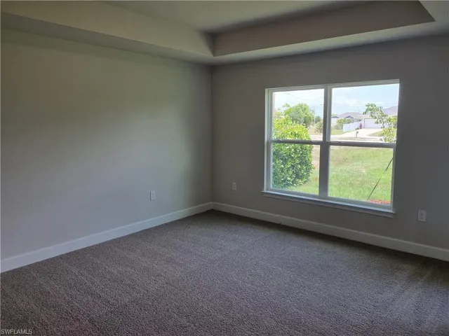 Carpeted spare room featuring baseboards