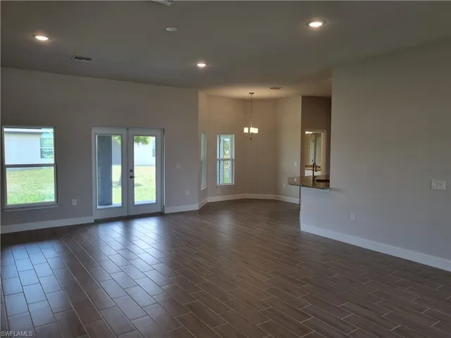 Empty room featuring recessed lighting, baseboards, dark wood finished floors, and french doors