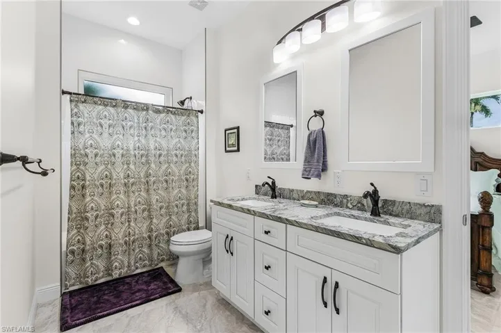 Full bath featuring double vanity, toilet, a shower with curtain, and tile floors